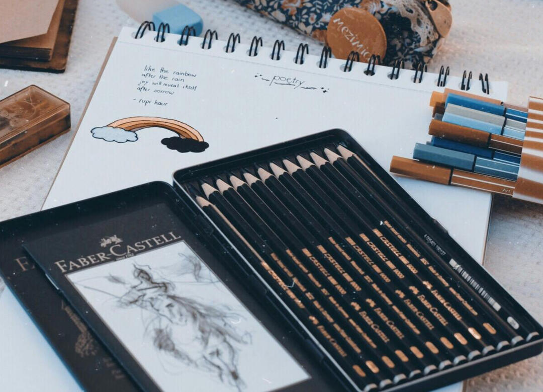 Notes Picture of a black, rectangular tin pencil case filled with black pencils and markers on top of a notepad