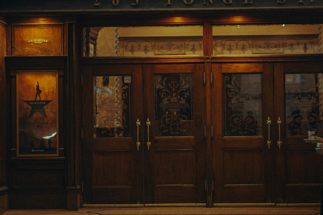 threshold picture of a woman walking past a set of doors while holding a tray of cups of coffee