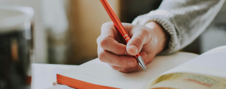 Inspiration vs. Copycatting hand holding a pen to write on a notebook